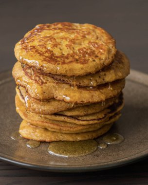 Üzerinde şurup olan kabak kabaklı krep yığınının yakın plan fotoğrafı.