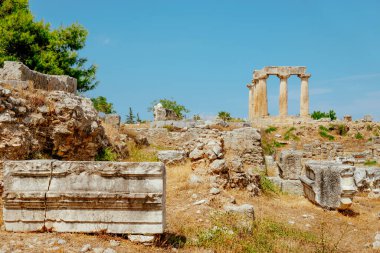 Yunanistan 'daki Antik Korint arkeolojik sahasının arka planda Apollo Tapınağı' nın kalıntılarını vurguluyor.