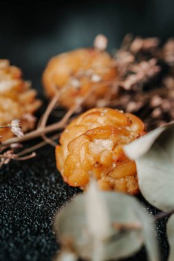 Bazı farklı panellere yakın çekim, Katalonya, İspanya 'dan tipik şekerlemeler, Azizler Günü' nde tatlı olarak yenir, karanlık bir yüzeyde, bazı kurumuş aromatik bitki dallarının yanında