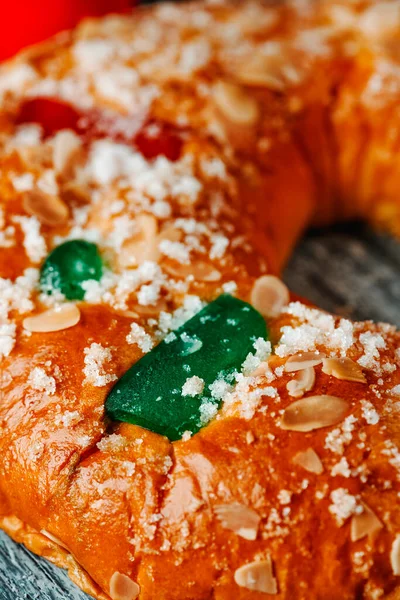 closeup of a roscon de reyes, the spanish king cake eaten traditionally on epiphany day, ornamented with some pieces of glazed fruit, some slices of almond and chunks of sugar