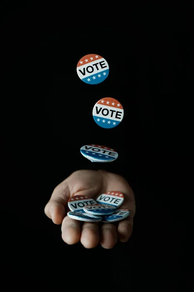 黒人を背景に男性の手に落ちる米国の選挙のためのいくつかの投票バッジ — ストック写真