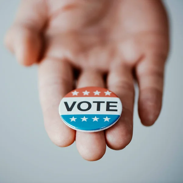 白人を背景にアメリカの選挙のための投票バッジを持つ若い男の閉鎖 — ストック写真