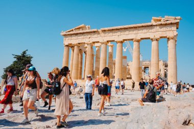 Atina, Yunanistan - 30 Ağustos 2022: Yunanistan 'ın Akropolis kentinde ünlü Parthenon' un kalıntıları önünde bir yaz günü bir grup ziyaretçi