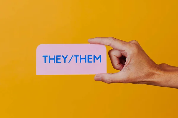 一个拿着粉色标志的人的特写 带有代词 在一个橘黄色的背景下 — 图库照片