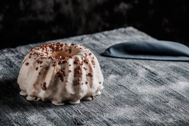 Gri bir ahşap masada vanilyalı kremayla kaplı lezzetli bir gugelhupf kekine yakın plan.