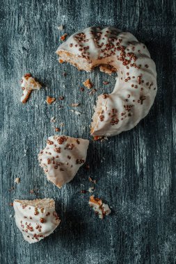 Gri bir ahşap masa üzerinde vanilyalı kremayla kaplı bir gugelhupf kekinin yüksek açılı görüntüsü.