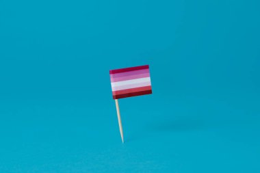 Mavi arka planda duran bir direğe bağlı lezbiyen bayrağının yakın çekimi