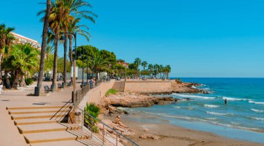 Alcala de Xivert, İspanya - 2 Ekim 2022: Alcossebre, Alcala de Xivert, İspanya 'da Vista Alegre gezinti güvertesinde yürüyen insanlar, Carregador plajının yanında, bazı insanların güneşin keyfini çıkardıkları yerde