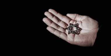 a star of david tied with some barbed wire in the hand of a man, on a black background with some blank space on the left