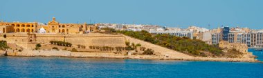 a view of the Fort Manoel in Manoel Island, Gzira, Malta, on a sunny summer day, and the city of Sliema in the background, in a panoramic format to use as web banner or header