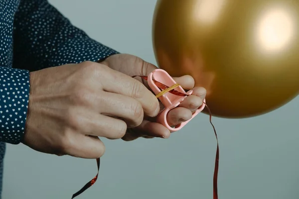 Closeup Man Using Tool Tie Inflated Golden Balloon Ribbon Gray — Stockfoto