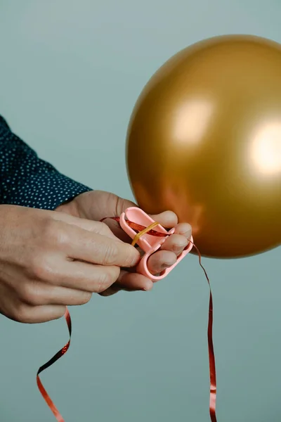 Man Uses Tool Tie Inflated Golden Balloon Red Ribbon Front — Zdjęcie stockowe