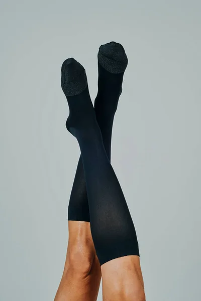 closeup of the legs of a man upside down wearing compression socks, on an off-white background