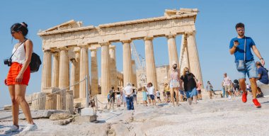 Athens, Greece - August 30, 2022: A crowd of people are visiting  the Acropolis of Athens, in Greece, in front of the remains of the famous Parthenon