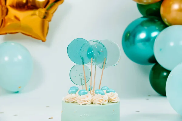 closeup of a nice blue cake and some balloons of different colors and sizes forming an elegant decoration for a birthday party a wedding or a baby cake smash