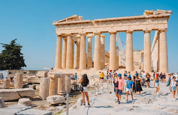 Athens, Greece - August 30, 2022: Visitors in the Acropolis of Athens, Greece, want to look closely the remains of the famous Parthenon, on a sunny summer day