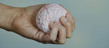 a man is squeezing a fake brain in his hand, in a panoramic format to use as web banner or header