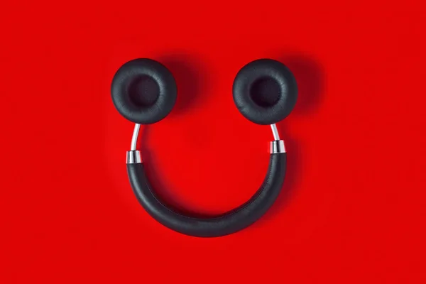 笑顔のような黒いワイヤレスフルサイズのヘッドフォンが赤い背景にあります — ストック写真