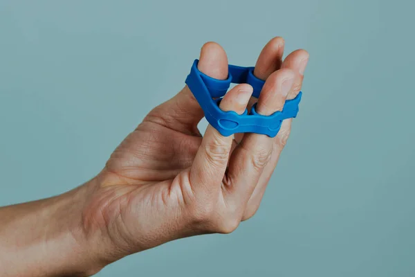 Homem Usa Uma Faixa Elástica Azul Para Exercitar Dedos Frente — Fotografia de Stock