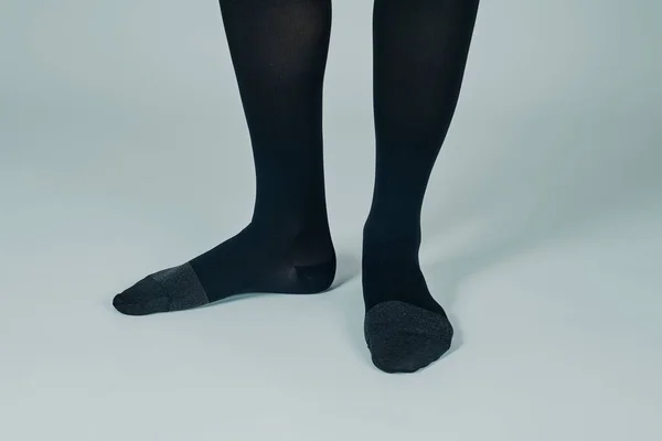 Крупный План Ног Стоящего Небелом Фоне Человека Черных Компрессионных Носках — стоковое фото