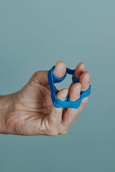 파란색 고무줄을 사용하여 위에서 손가락을 운동하는 남자의 — 스톡 사진