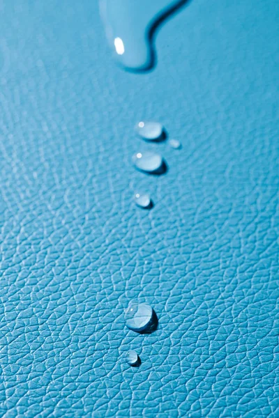Close Van Enkele Druppels Water Een Blauw Lederen Oppervlak — Stockfoto