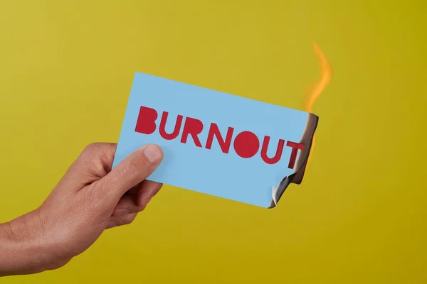 Closeup Man Holding Blue Sign Fire Text Burnout Yellow Background — Stock Photo, Image
