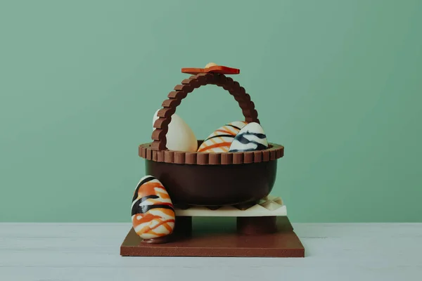 带鸡蛋的巧克力篮子 是教父或母亲送给复活节教子的一种传统甜点 放在绿色背景的木制桌子上 — 图库照片