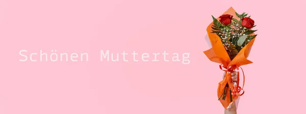 赤いバラの花束を手にした男とピンクの背景にドイツ語で書かれた幸せな母親の日のテキストウェブバナー形式として使用するパノラマ形式で — ストック写真