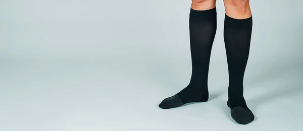 Muž Stojící Téměř Bílém Pozadí Nosí Černé Kompresní Ponožky Panoramatickém — Stock fotografie