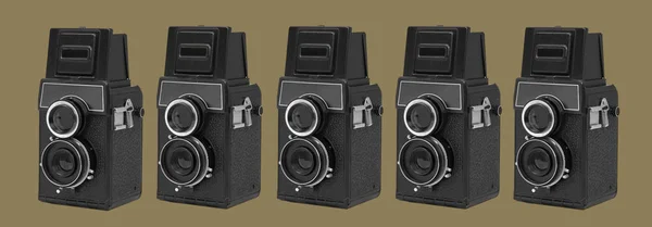 some black retro medium format film cameras on an olive green background in a panoramic format to use as web banner or header