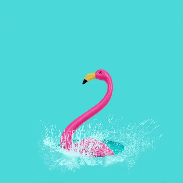 一只假粉红火烈鸟在蓝色背景的水坑里飞溅的特写镜头 — 图库照片