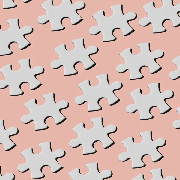 淡いピンクの背景に異なる線で配置された白いパズルピースのパターン — ストック写真