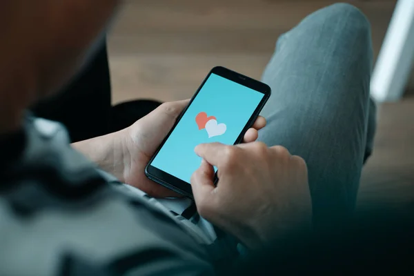 カジュアルな服装の男の閉鎖 ソファに座って モックを使用してオンライン日付彼のスマートフォン上のアプリ — ストック写真