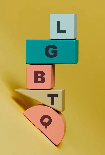 木のブロックに書かれたLgbtqという言葉は黄色の背景に異なる色と形を持ち多様性という概念を表しています — ストック写真