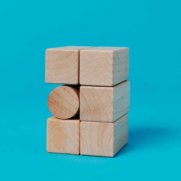 在一堆矩形玩具块中的圆柱形玩具块 蓝色背景 正方形格式 — 图库照片