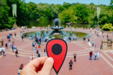 Güneşli bir bahar gününde, New York 'ta, Central Park' ta Bethesda Terrace 'ı gösteren kırmızı bir işaret taşıyan bir adamın eli.