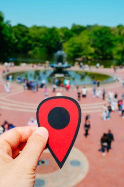 Bir adamın eli, güneşli bir bahar gününde New York, New York 'taki Central Park' ta Bethesda Terrace 'ı gösteren kırmızı bir işaret tutuyor.