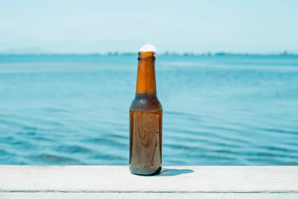 天気の良い桟橋で夏の日に水の隣に爽やかなビールを1本 — ストック写真