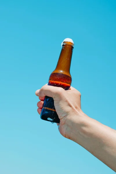 特写一个男人手里拿着一瓶啤酒在天空中倒立 — 图库照片