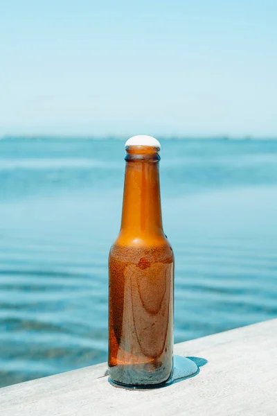 Suyun Yanındaki Yıpranmış Bir Iskelede Serinletici Bir Bira Şişesine Yakın — Stok fotoğraf