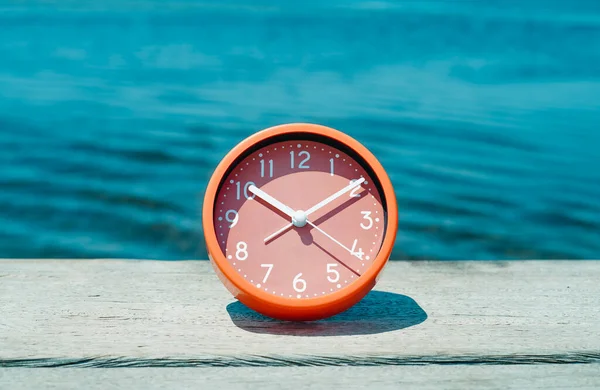 天気の良い木の桟橋でピンクの時計を閉めた水の隣の夏の日 — ストック写真