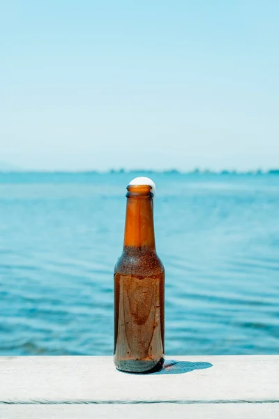 夏天的一天 在码头上 在水边的一个小码头上 有一瓶清爽的啤酒的特写 上面有一些空白的地方 — 图库照片