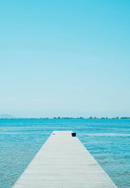 夏の日に黒いフリップフロップと黒いバケツのペアで水につながる風化した木製の桟橋 — ストック写真