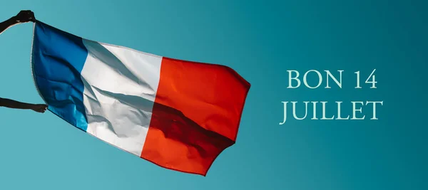 举着一面法国国旗在空中飘扬 文字带着7月14日的欢乐 7月14日是法国国庆节 用法语书写 以全景形式作为网页横幅 — 图库照片