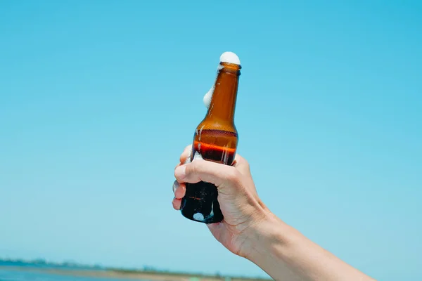 一个高加索人手里拿着一个啤酒瓶在天空中 在一片自然景观前 — 图库照片