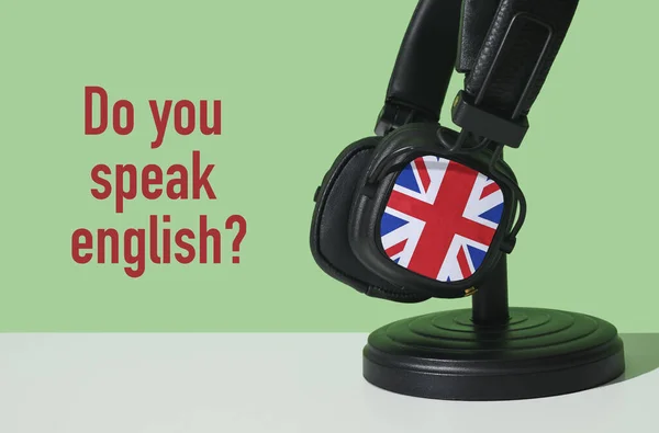 the question do you speak english and a pair of headphones patterned with the flag of the united kingdom, on a white surface, in front of a green background