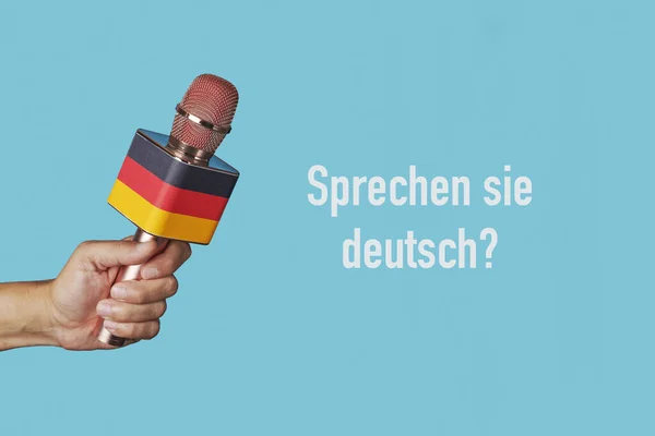 the question do you speak german written in german and the hand of a man holding a microphone patterned with the german flag against a blue background