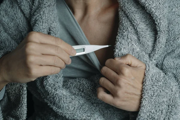病気の男性を閉じ込め 自宅で ふわふわの灰色の家服を着て デジタル温度計で温度を測る — ストック写真
