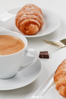 a cup of coffee and some xuixos de crema, pastries filled with custard typical of catalonia, spain, on a set table clipart
